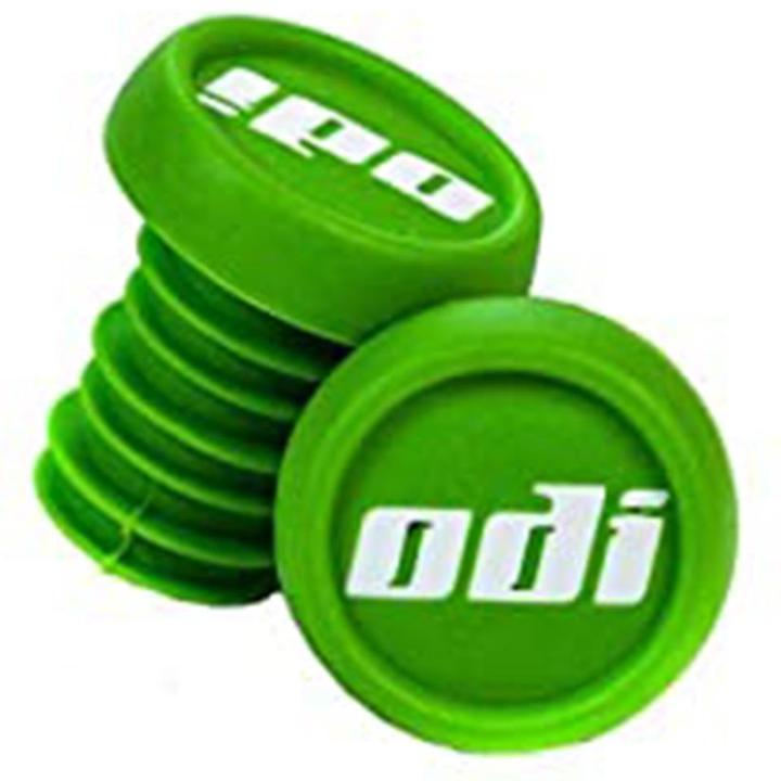 A set of ODI Push-In Stunt Scooter Bar Ends in green features the brand's name "odi" in white. One bar end is positioned upright, while the other is slightly angled, showcasing their ribbed structure and resin material for a secure fit and customizable scooter bar experience.