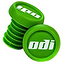 A set of ODI Push-In Stunt Scooter Bar Ends in green features the brand's name "odi" in white. One bar end is positioned upright, while the other is slightly angled, showcasing their ribbed structure and resin material for a secure fit and customizable scooter bar experience.