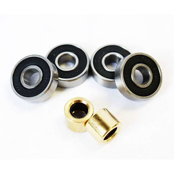 Four Ethic DTC Scooter Bearings with black centers and two small brass bushings are neatly arranged on a white background, perfect for your next scooter upgrade.