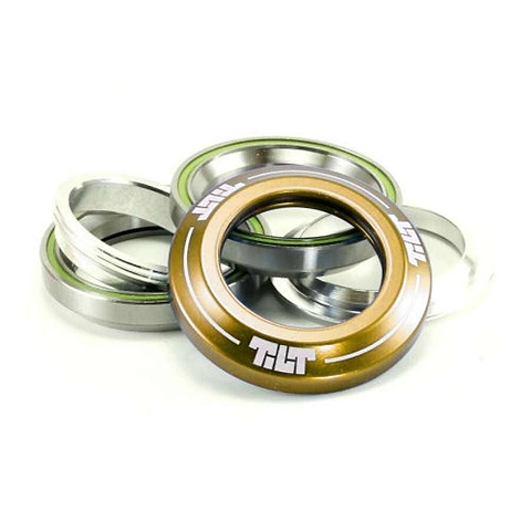 A stack of Tilt Integrated Stunt Scooter Headsets in gold is displayed, showcasing green accents and precision-sealed bearings with an anodized dust cover and a copper-colored top piece prominently in the foreground against a plain background.