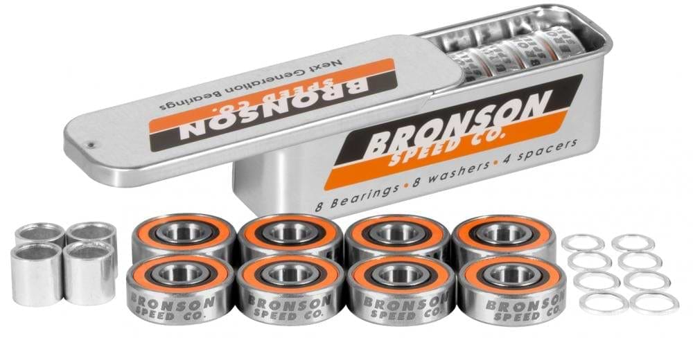 Inside the metal box featuring "Bronson," you will find Bronson Speed Co. G3 Skateboard Bearings - 8 Pack, alongside washers and spacers. The high-speed ceramic oil guarantees peak performance for the deep groove raceways. Stylishly accented in orange and black, these bearings are arranged in two tidy rows next to the open box.