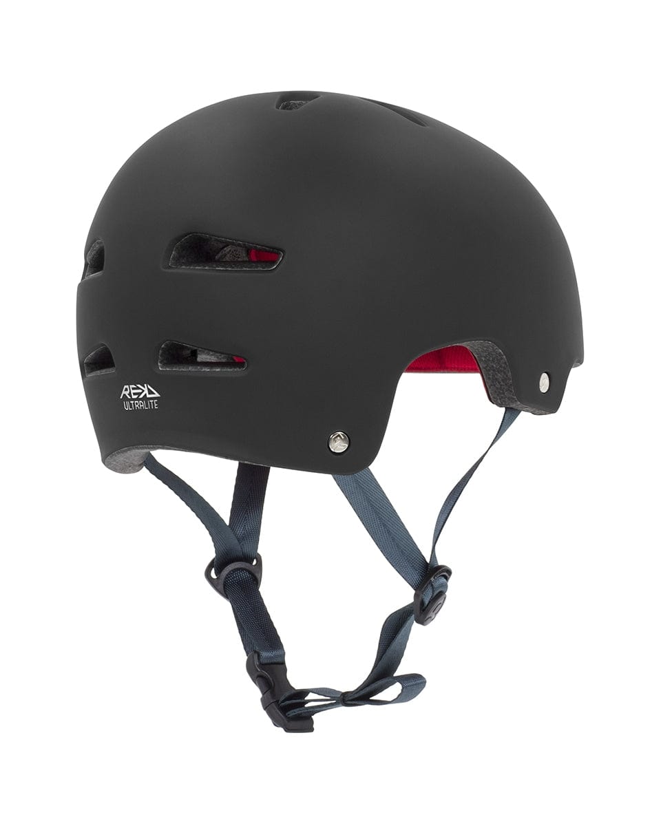 A sleek black REKD Ultralite In-Mold Skate/Scooter Helmet, ideal for action sports. It boasts ventilation slots on the sides and a gray adjustable chin strap. The interior lining is red, providing a lightweight design for comfort. The REKD brand logo is prominently featured on the side.