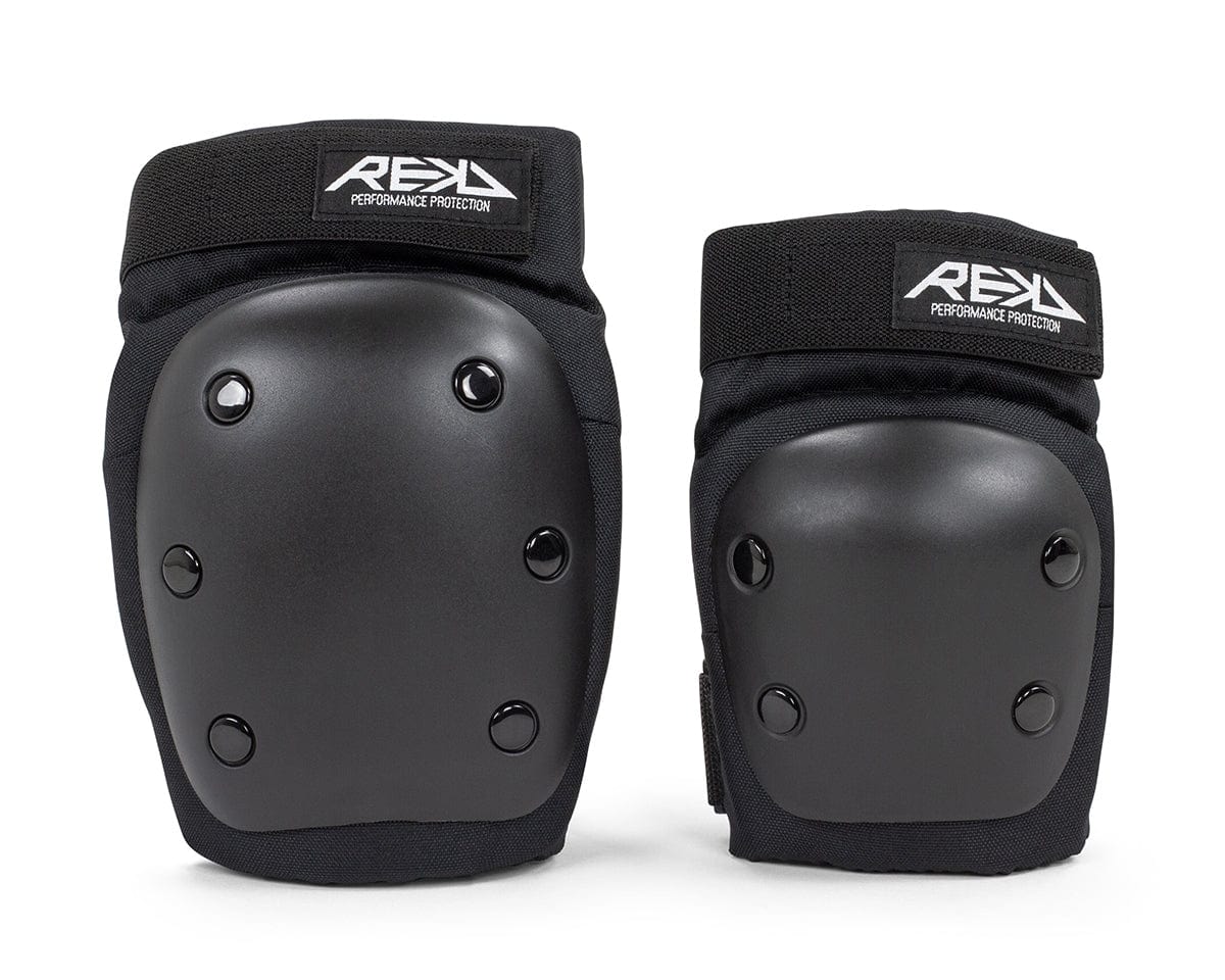 A pair of black knee pads from the REKD Youth Heavy Duty Double Skate Protection Pad Set are shown against a white backdrop. Designed for heavy-duty protection, they include hard outer shells and soft inner padding to ensure safety during intense activities. Each pad proudly displays the "REKD" brand label, symbolizing quality and reliability.