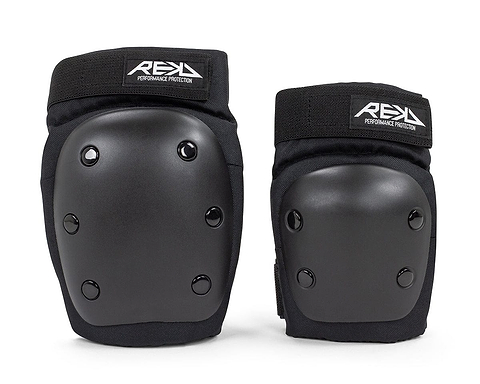A pair of black knee pads from the REKD Youth Heavy Duty Double Skate Protection Pad Set are shown against a white backdrop. Designed for heavy-duty protection, they include hard outer shells and soft inner padding to ensure safety during intense activities. Each pad proudly displays the "REKD" brand label, symbolizing quality and reliability.
