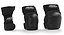 Three black protective gear items from REKD are showcased: an ergonomic wrist guard on the left and two knee or elbow pads on the right. The REKD Junior Heavy Duty Triple Skate Protection Pad Set includes hard plastic shells with the "REKD" logo on the straps, providing protection for extreme sports enthusiasts.