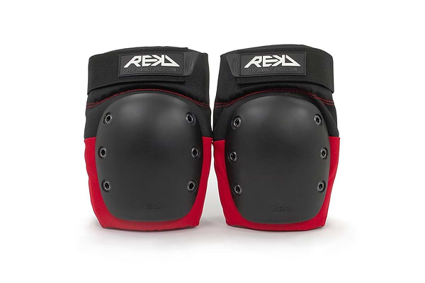 A pair of REKD Ramp Knee Skate Protection Pads in black and red, featuring hard black caps with the "REKD" logo on top. Designed for action sports, these knee pads provide impact resistance suitable for skateboarding and rollerblading.