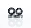 Four Skates.co.uk ABEC 9 Black Scooter Bearings, similar to those in a stunt scooter, are displayed in a staggered line with two standing and two lying flat. The metallic bearings showcase black inner rings against a simple white background, suggesting precision akin to their ABEC 9 ratings.
