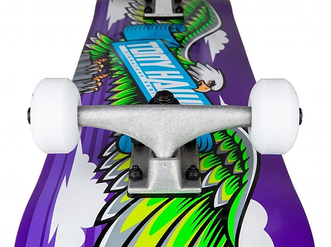 The Tony Hawk 180 Series Wingspan Complete Skateboard, measuring 7.75" x 31", showcases a striking design with green and yellow wings alongside a white bird of prey set against a purple background. This complete skateboard is equipped with white wheels, silver trucks, and a robust 7-ply maple deck to ensure optimal performance.