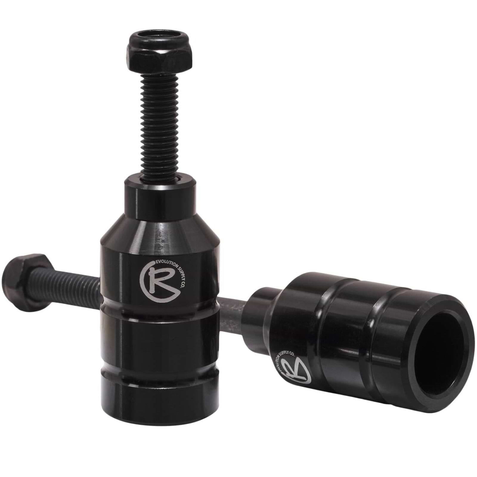 Two black Revolution Aluminium Stunt Scooter Pegs, designed from CNC milled aluminum, feature a cylindrical shape with a bolt on top for easy installation and the "R" logo on the side. Built to enhance your scooter's performance and durability, they offer precision engineering for stunts.