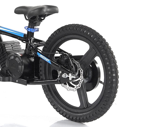 The image features a close-up of the rear wheel and seat of a Revvi 16" Plus Kids Electric Balance Bike in black with blue accents. It showcases its disc brake and wide, rugged tire with a distinct tread pattern, ideal for those who value quality in children's electric bikes. Notably, this model is available in an Orange variant under the Revvi brand name.