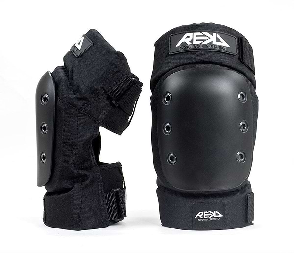 The REKD Pro Ramp Skate Protection Knee Pads in black include two knee pads, each designed with a hard outer shell and impact pro caps. The adjustable straps provide a secure fit, while the branding "REKD Performance Protection" is prominently displayed on each pad. One knee pad is positioned upright, and the other leans to the side, showcasing its ergonomic knee recesses from various angles.