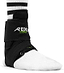A foot encased in a white sock is comfortably supported by the black REKD Energy Covert Ankle Skate Protection Brace, delivering strong protection for the ankle. The brace is securely fastened with straps, and a black and white striped sock emerges above it, highlighting both style and stability.