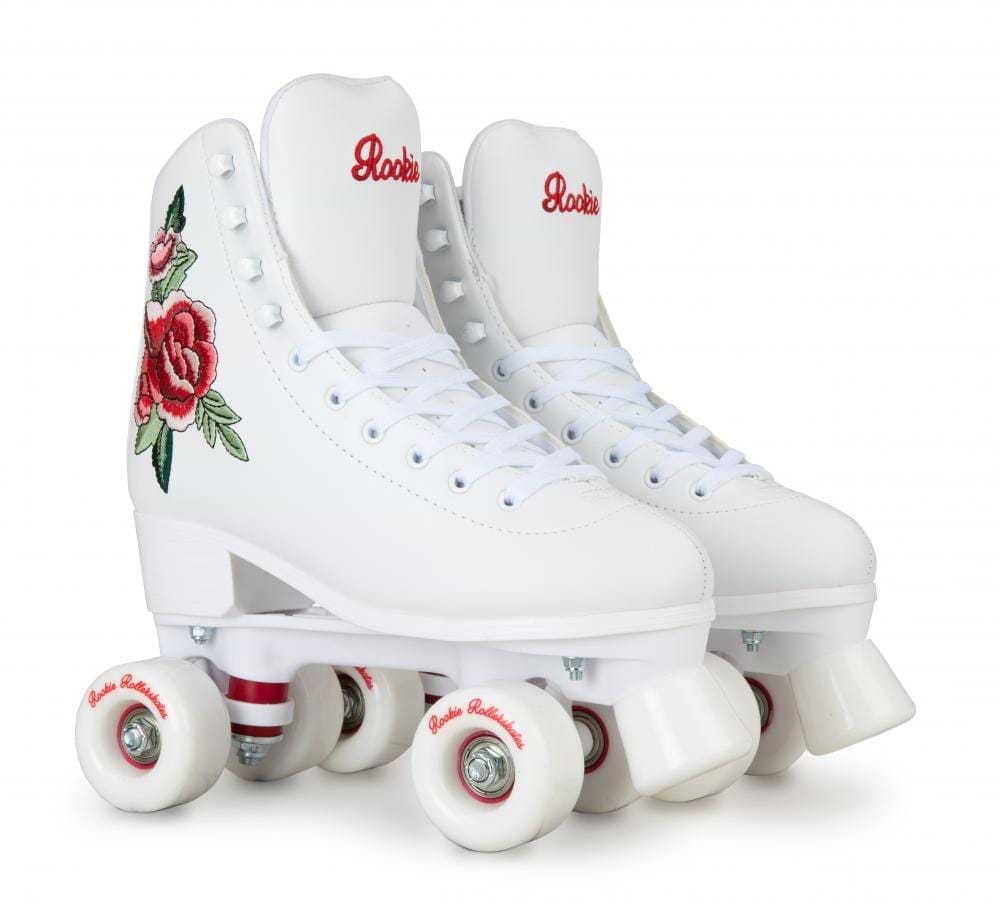 The Rookie Rosa Quad Roller Skates - White, from the brand Rookie, are crafted using vegan-friendly materials. These stylish white roller skates are adorned with elegant red embroidered designs on the sides. They feature durable white wheels and have "Rookie" proudly inscribed on the tongue, combining both style and ethical design.