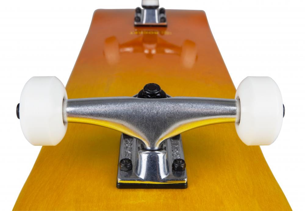 A close-up of the underside of the Rocket Double Dipped Orange / Yellow Complete Skateboard showcases its aluminum trucks and white wheels. The wooden deck, made from 7-ply hardrock maple, features a distinct brownish-orange finish.