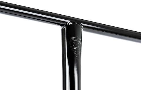 Close-up of a glossy black metal T-joint featuring a small engraved shield logo reading “TENN” on the vertical bar, showcasing the exceptional craftsmanship of the Ethic DTC Tenacity V2 Steel Oversized HIC Stunt Scooter T-Bars in Black Mirror (770mm x 600mm). Manufactured by Ethic, these oversized chromoly steel bars deliver outstanding strength and durability for demanding riders.