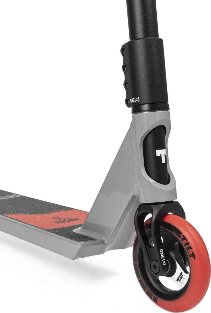 Close-up of the front part of the Tilt Passage Build Pro Complete Stunt Scooter - Red, which showcases a robust T-Bar. The image highlights the front wheel, deck, and section of the handlebar. The wheel is red with black accents, while the 6061 aluminum deck features a textured surface to ensure optimal grip.