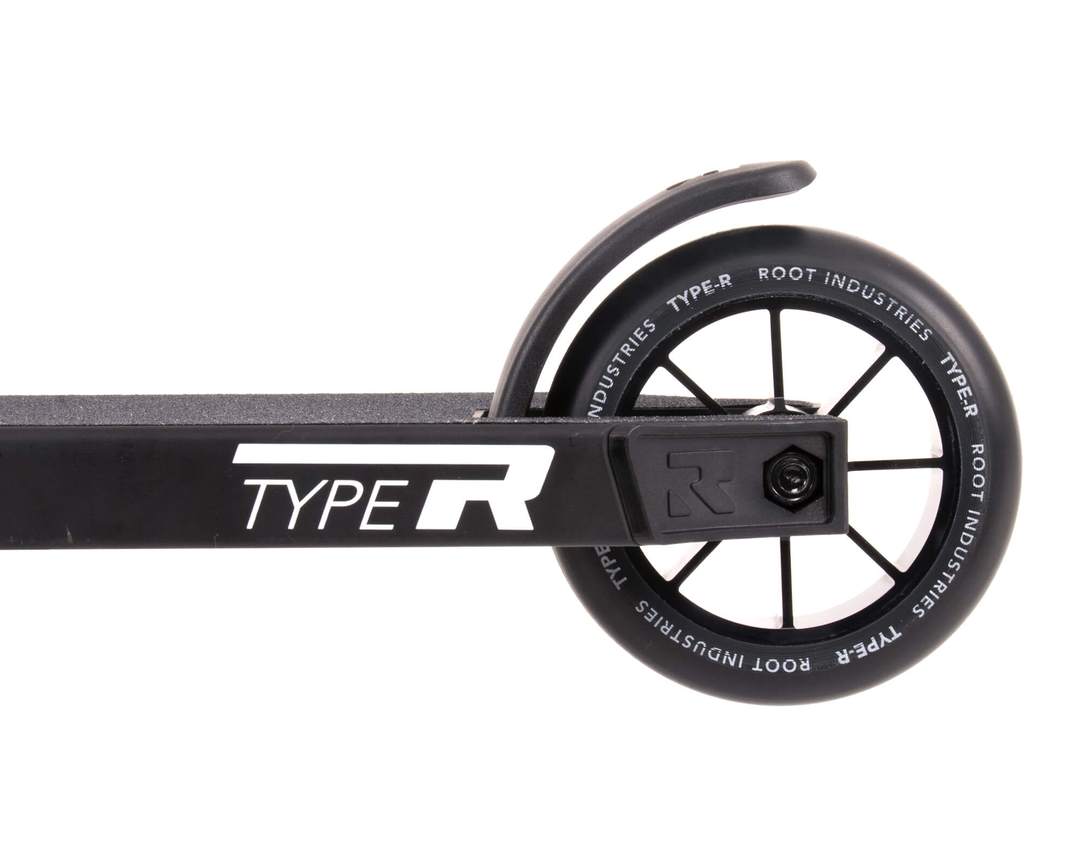 The close-up of a wheel on the Root Industries Type R Complete Stunt Scooter - Black features "ROOT INDUSTRIES TYPE R" printed on the rim, emphasizing its sleek design. This minimalist aesthetic is echoed in the frame, which also prominently displays "TYPE R," with the wheel smoothly integrated into a streamlined deck.