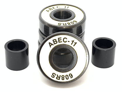 A close-up of three Logic ABEC 11 White Scooter Bearings stacked vertically, with two additional bearings from the same 4-pack lying on their sides nearby. The black bearings, featuring white labeling around the center opening, are designed for optimal performance speed.
