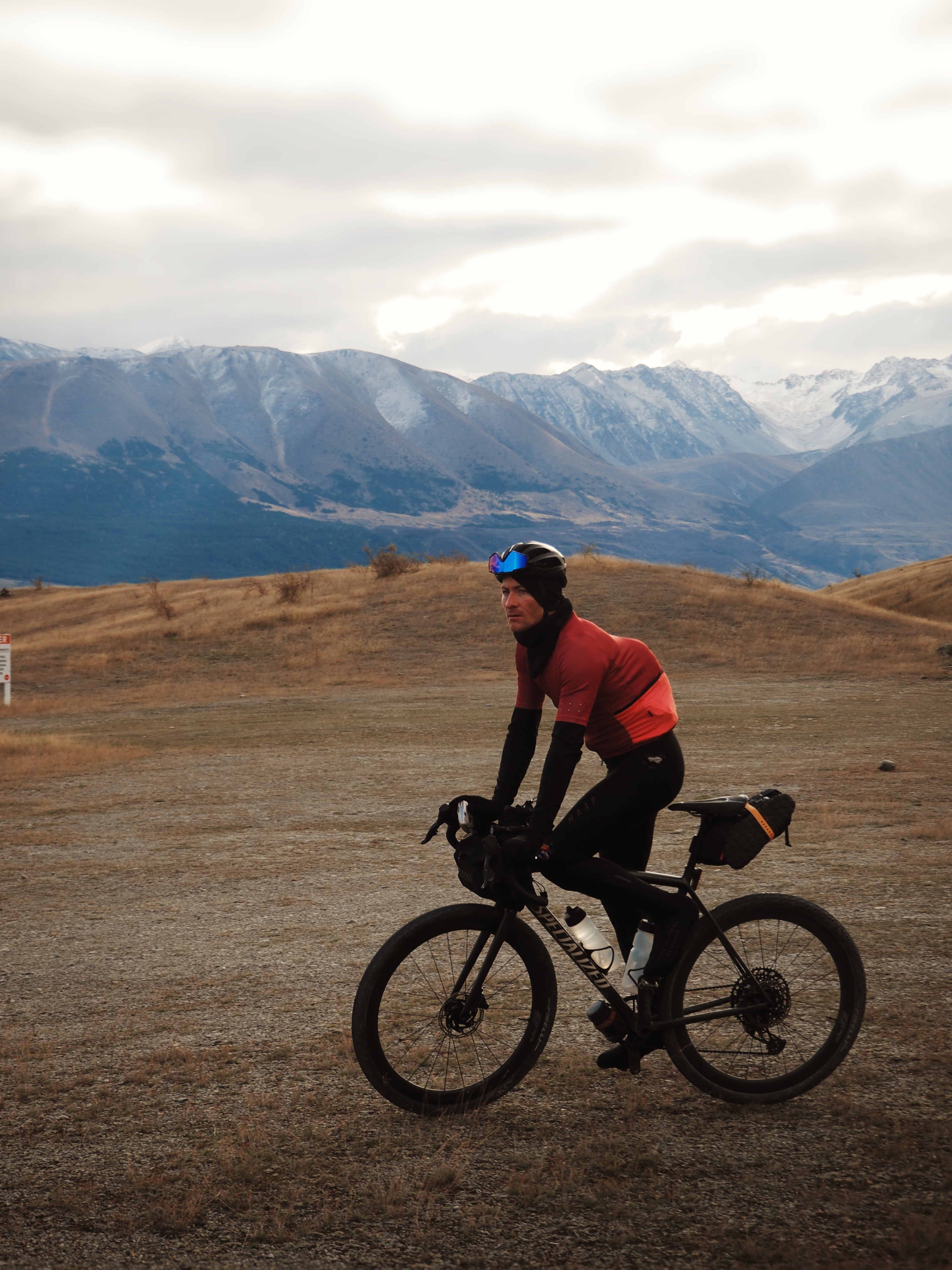 A cyclist slows down to take in the view, mountains in the background at sunset