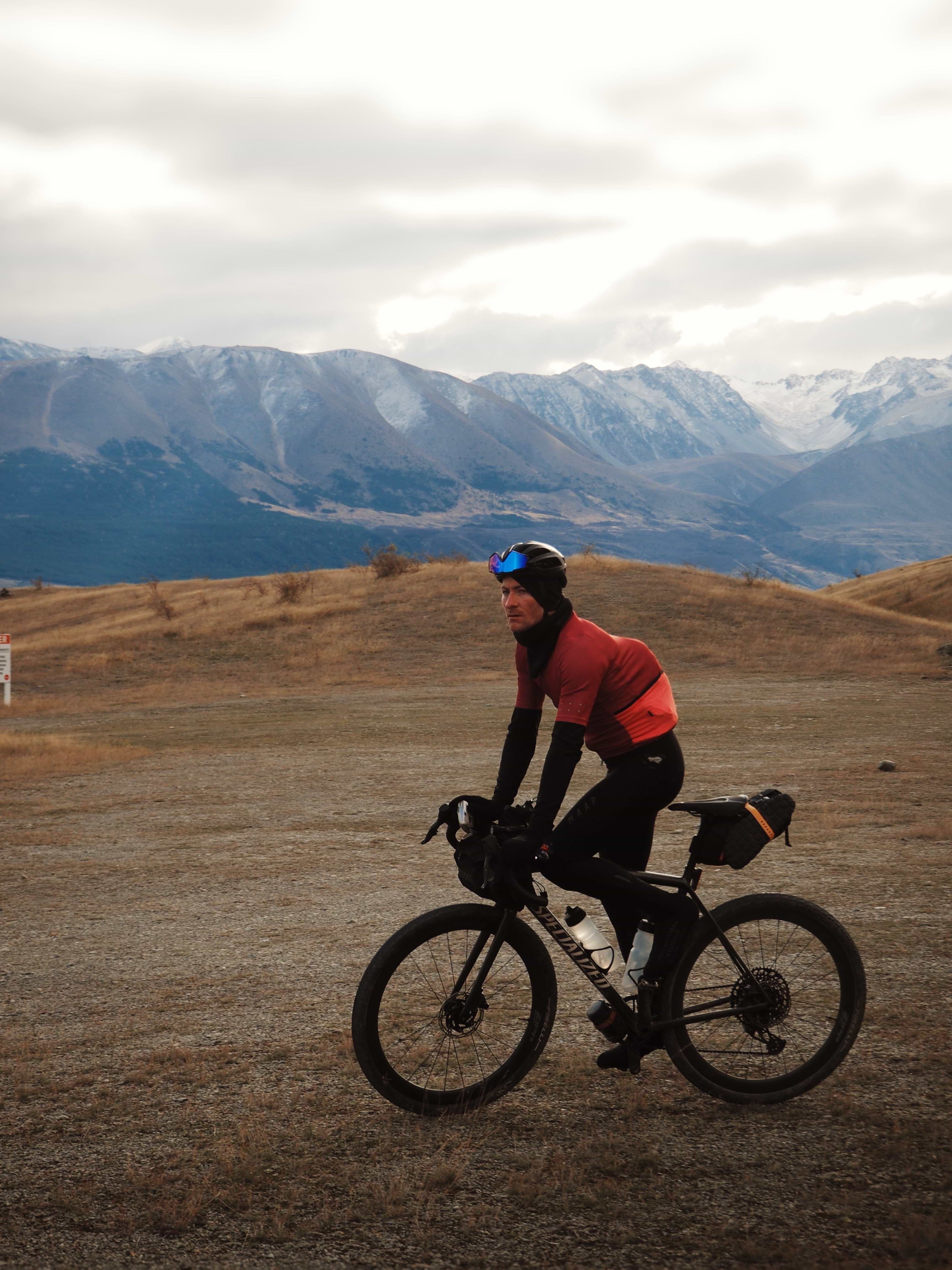 A cyclist slows down to take in the view, mountains in the background at sunset