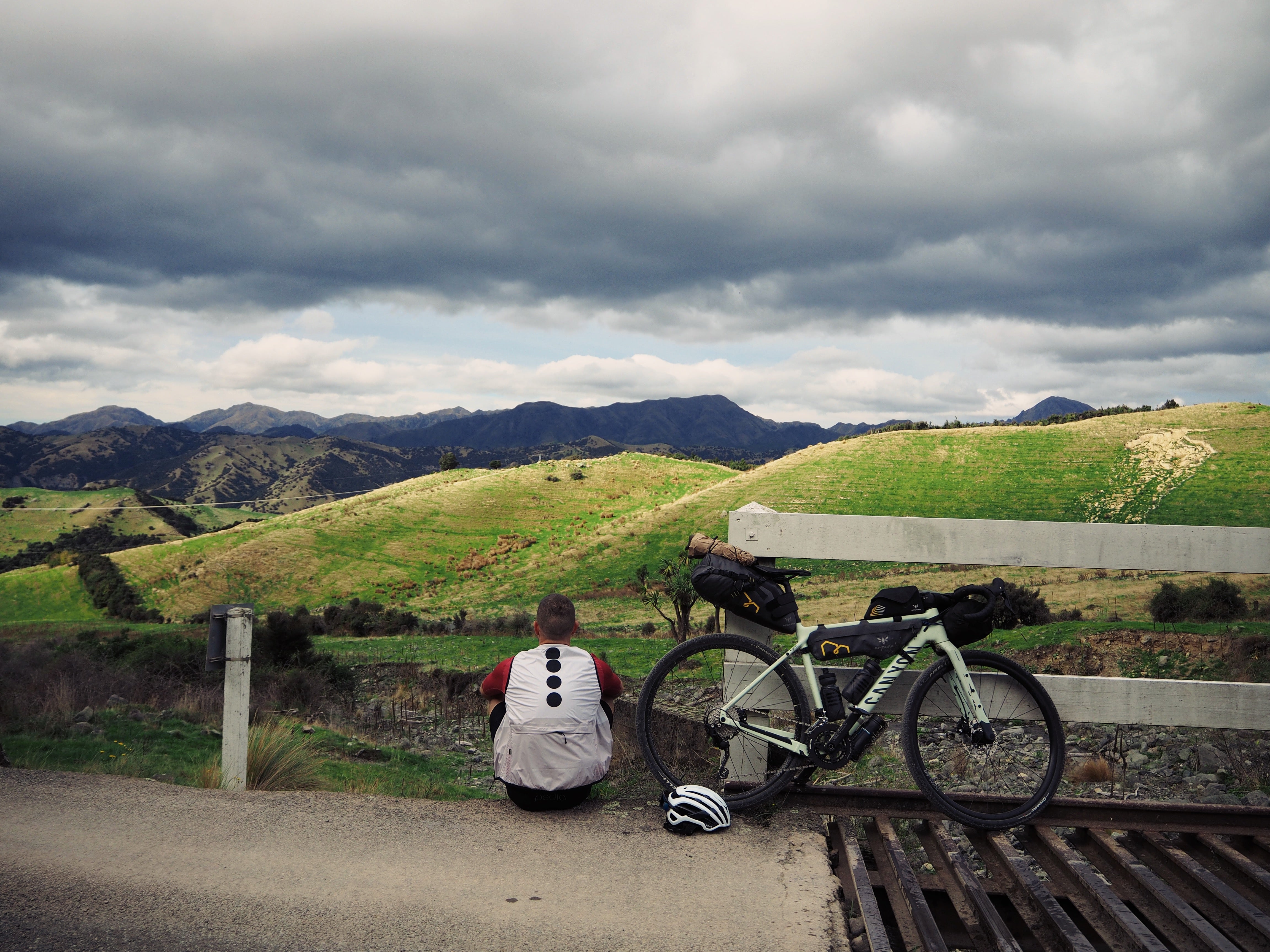 Cyclist sits down next to their bike looking over a grand vista
