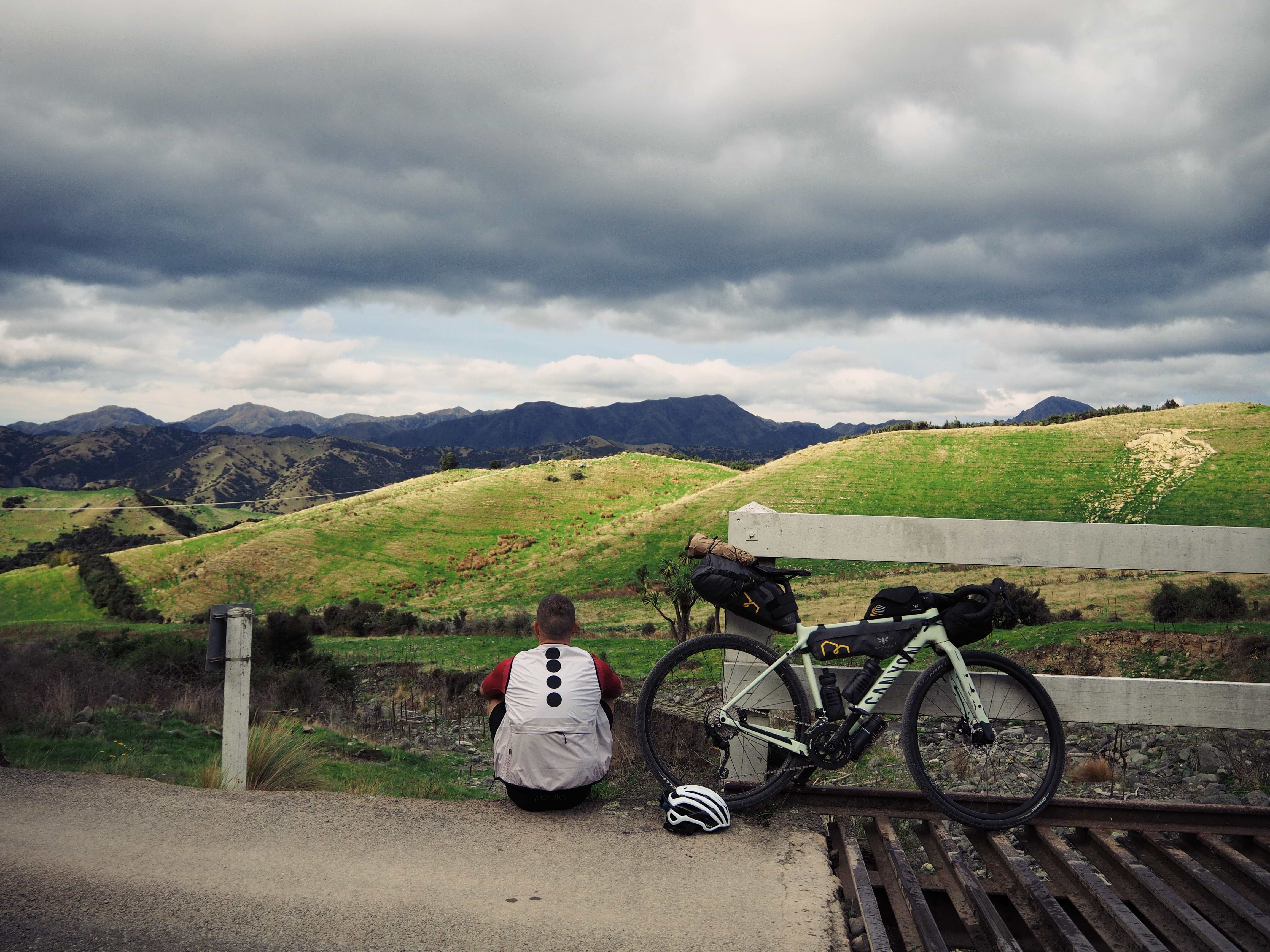 Cyclist sits down next to their bike looking over a grand vista