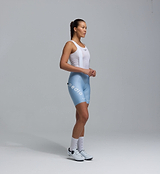 Pedla Women's SuperFIT 2.0 powder blue cycling bib shorts on model, side view — Italian fabric, Elastic Interface chamois, advanced brace support, seamless cuff, reflective logos, aerodynamic