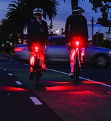 Project Flock Rear Light providing Biomotion visibility, on model's back, enhancing road safety.