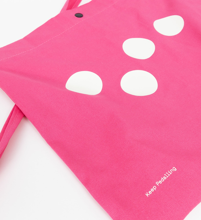 Pedla pink polka-dot musette bag with "Keep Pedalling" logo — lightweight road cycling feed bag, open-compartment crossbody strap for one-handed access and quick refuels