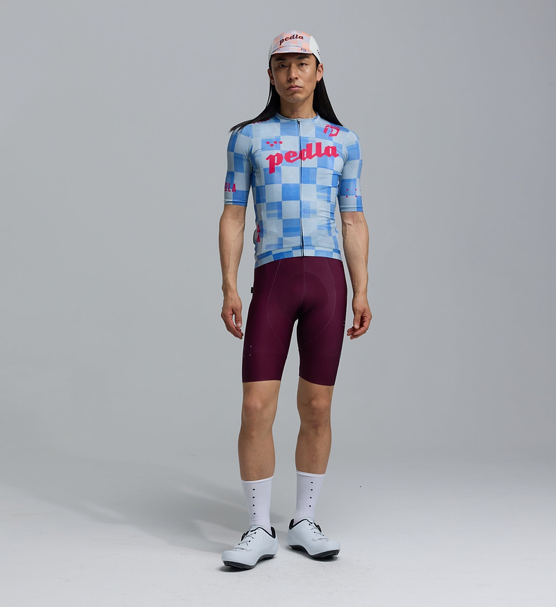 Heritage men's training cycling jersey — blue checkers pattern, breathable perforated panels, UPF 30+ sun protection, 83% REPREVE recycled polyester/17% elastane, silicone gripper hem, extended sleeves, low collar, microfiber moisture-wicking, four-way stretch, all-season road and training bike jersey.