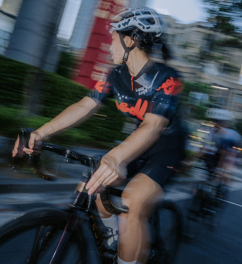 Local Loops Women’s Pro Air Gravel one-piece cycling suit in black — ultralight, breathable gravel and road race skinsuit with compressive bib, high-stretch woven grid fabric, moisture‑wicking quick‑dry performance, integrated storage pockets, reflective accents and reinforced durable construction for endurance gravel, road and urban riding.