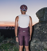 Rear view of rider wearing Pedla SuperSYSTEM men's fig cycling bib shorts, compressive Superfit fabric, EIT chamois, silicone leg grippers, integrated rear 1.5L hydration pocket with hose channel and side stash pockets, endurance/gravel-ready