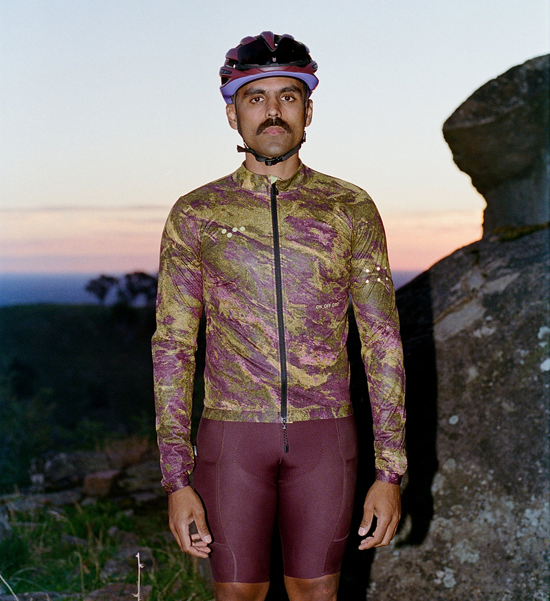 On Off Grid men's SuperSYSTEM cycling jacket, Multi Rock print, front view on model — lightweight windproof, water-resistant shell with breathable mesh panels, two-way SAB zipper, silicone hem and rear zip pack pocket