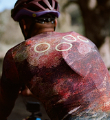 Close-up back of ON_OFF GRID SuperSYSTEM men's cycling jersey — red speckled print with circular reflective accents; ultralight, high-stretch, breathable, moisture-wicking performance for road, gravel and mixed-terrain riding