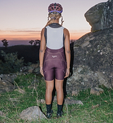 Pedla SuperSYSTEM women's fig cycling bib shorts back view, compressive Superfit fabric, integrated 1.5L hydration pocket with hose channel, EIT chamois, silicone leg grippers for endurance road and gravel riding