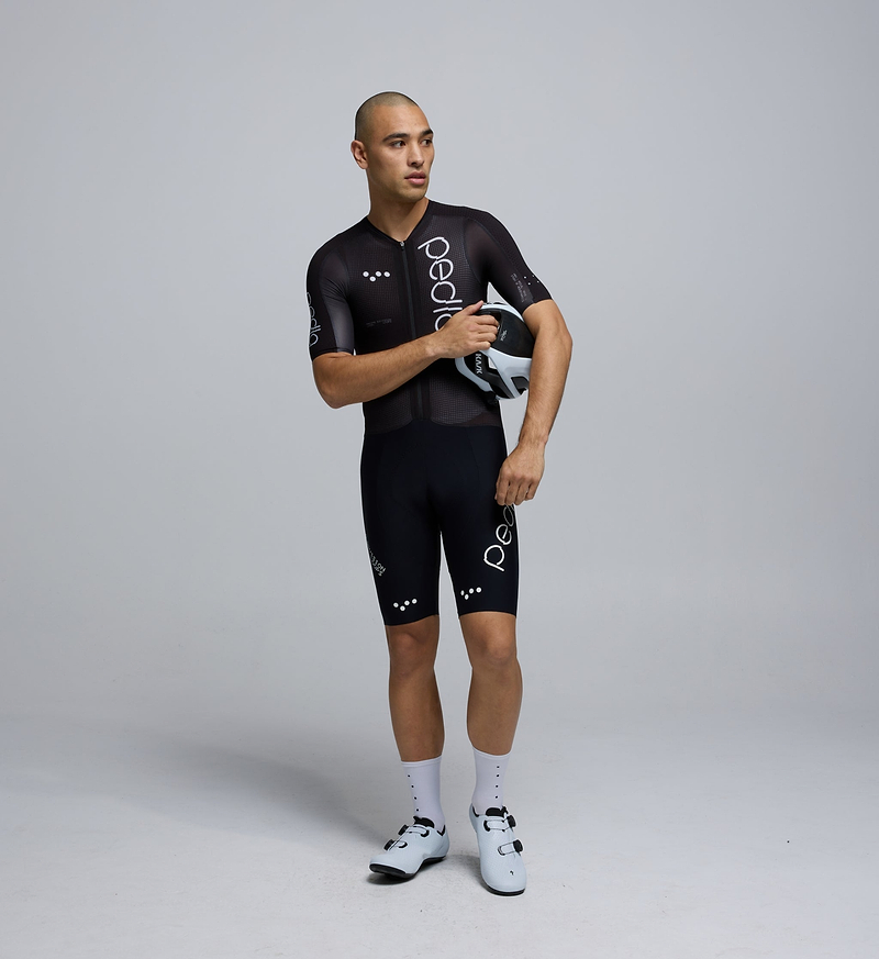 Front-facing image of a male cyclist wearing the Pro Pursuit Crit Suit in Black, highlighting the close-fitting aero cut, low-profile collar, and breathable woven fabric designed for speed.