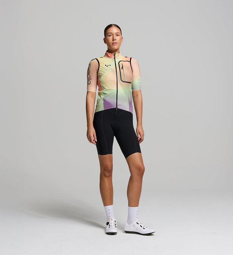 Cyclist wearing the Women’s Pro Deflect 2.0 Cycling Gilet in Peach, showcasing its streamlined fit, high stand collar, and breathable fabric.