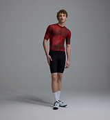 Men's deep-red Race Division training cycling jersey front view on model — short-sleeve performance road jersey with grid pattern, UPF 30+ sun protection, breathable perforated panels, silicone gripper hem, REPREVE recycled polyester, four-way stretch