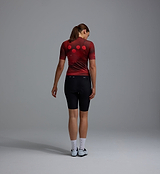 Women's Race Division training cycling jersey back view — deep red grid, breathable perforated panels, UPF 30+ sun protection, REPREVE recycled polyester, moisture-wicking, four-way stretch, silicone gripper hem