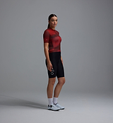 Women's Race Division training cycling jersey, deep red grid print, side view — breathable perforated panels, UPF 30+ sun protection, REPREVE recycled polyester, four-way stretch, silicone gripper hem, moisture-wicking road jersey