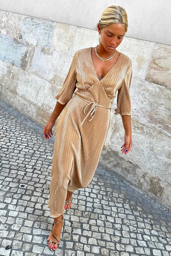 Gold Plisse Dress with angel sleeves and a tie waist worn by a model on a cobblestone street.