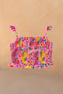 Girls Pink Fruit Crop Bikini Top featuring a shirred body and ruffle straps against a neutral wall.