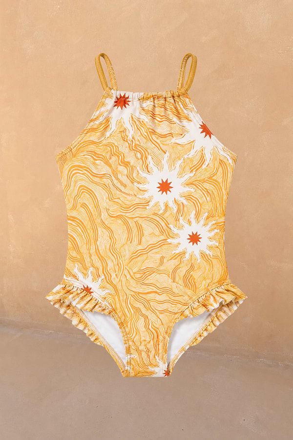 Girl's Yellow Sun Swimsuit featuring a sun print, thin straps and frill detailing against a neutral wall.