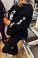 Black sweatshirt with ecru embroidery of heart, star and palm tree motifs on the sleeve, worn at a pilates studio.