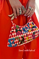 Red check Cirque Bag with hand-beaded motifs and a wooden handle, highlighting the hand-embellished glass bead details.