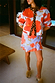 Blue Poppy Cardigan with bold orange poppy print and leopard trim, worn with a matching ruffled wrap skirt.