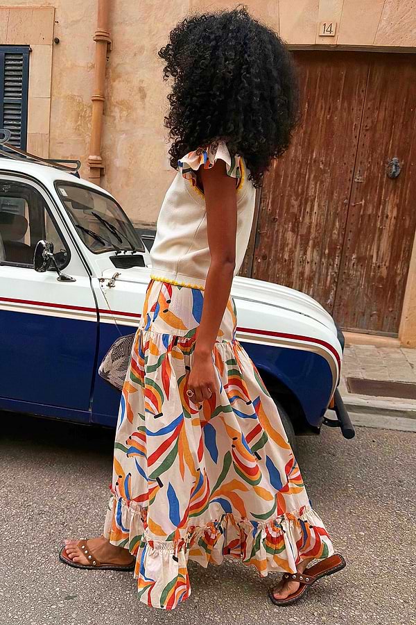 Banana Saige Skirt in a multicolour banana print with cotton tiered panels and a frill hem in a street setting.