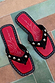 Black suede flat sandals featuring silver studs, a square toe, and a red logo footbed with white graphic details.