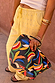 NFD banana print pouch with a black wrist strap, held by a model wearing studded yellow and white striped trousers.