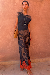 Top in jersey nero e cioccolato con pizzo marrone, abbinato a una gonna floreale su sfondo terracotta.